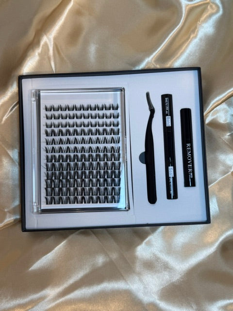 Alter Ego Cluster Kit open box showing jumbo tray of DIY cluster lashes, bond, seal, tweezers and remover on white satin fabric