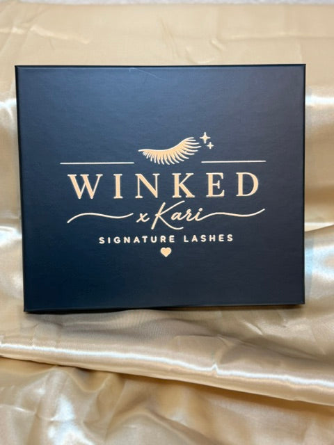 Winked x Kari Signature Lashes black and gold box for the Tease Cluster Kit on champagne satin fabric