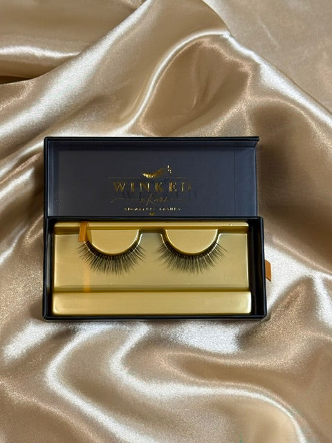Darling strip lashes in open black and gold Winked x Kari signature lashes box on champagne satin fabric
