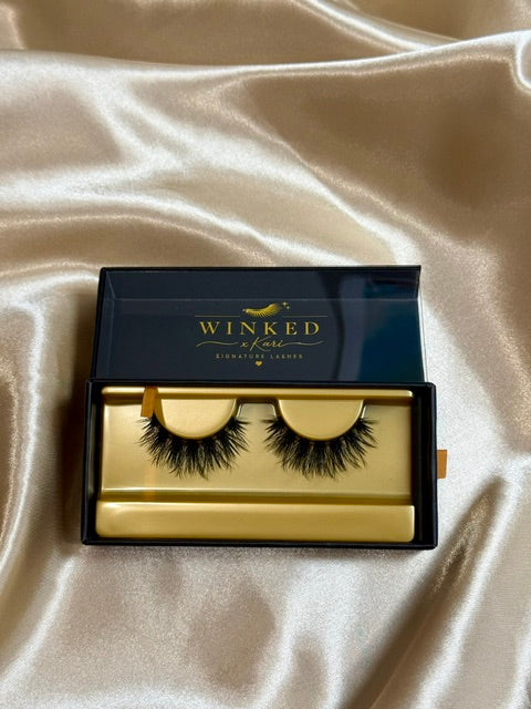 Honey strip lashes in open black and gold Winked x Kari box on satin fabric