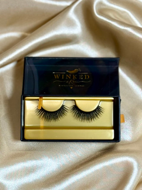 Icon strip lashes in open black and gold Winked Rose box on satin fabric