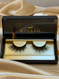 Muse strip lashes in open black and gold Winked x Kari signature lashes box on champagne satin fabric