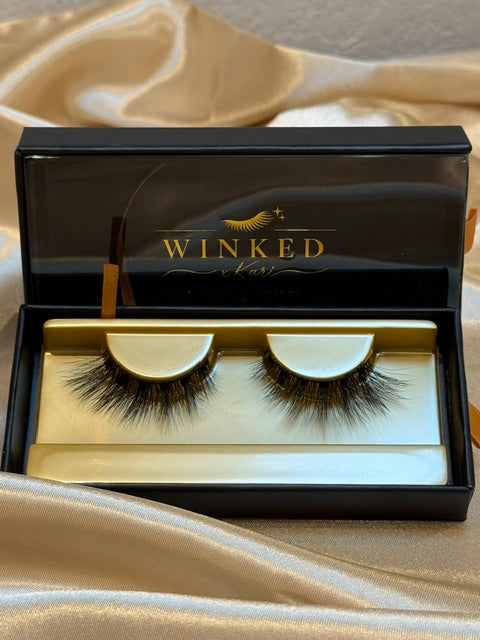 Muse strip lashes in open black and gold Winked x Kari signature lashes box on champagne satin fabric