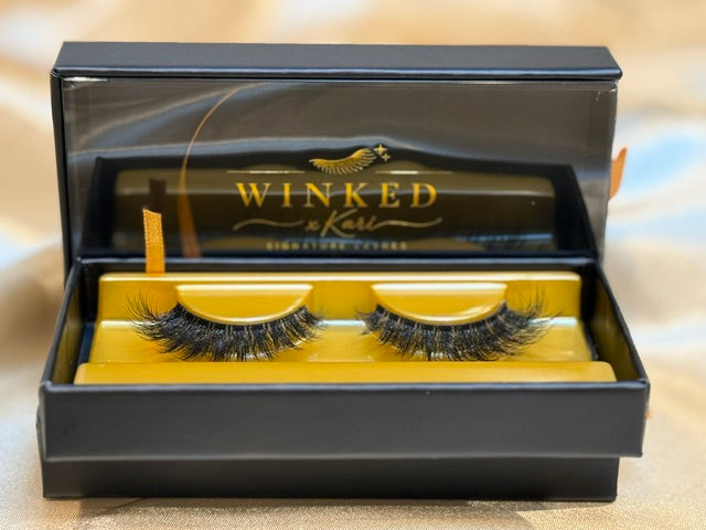 Noir strip lashes displayed in open black and gold Winked x Kari signature lashes box showing dramatic full volume