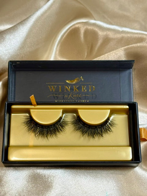 Obsessed strip lashes in open black and gold Winked Rose box on satin fabric