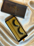 Runway strip lashes in gold Winked x Kari tray inside open black signature lashes box on white satin fabric