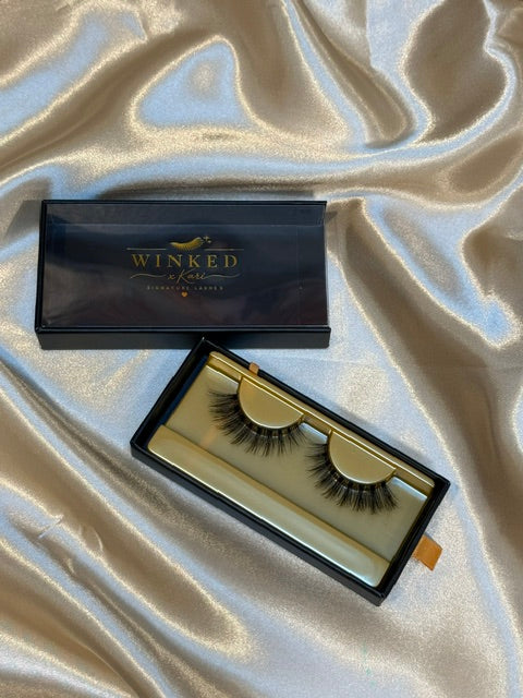 Subtle strip lashes in open black and gold Winked x Kari box on silver satin fabric