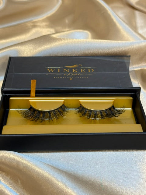 Subtle strip lashes angled view in open black and gold Winked x Kari signature lashes box