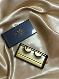 Trinity strip lashes in black and gold Winked Rose packaging on satin fabric