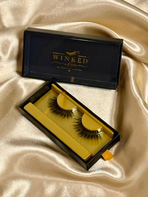 Trinity strip lashes displayed in open black and gold Winked Rose box on satin fabric