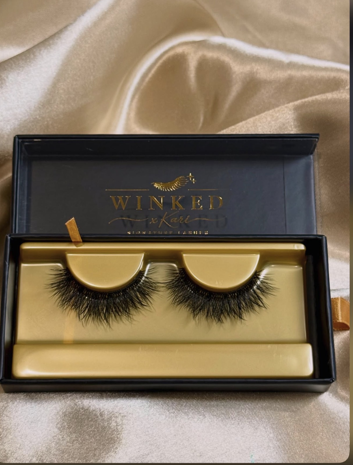 Obsessed strip lashes in a black and gold Winked x Kari box on champagne satin